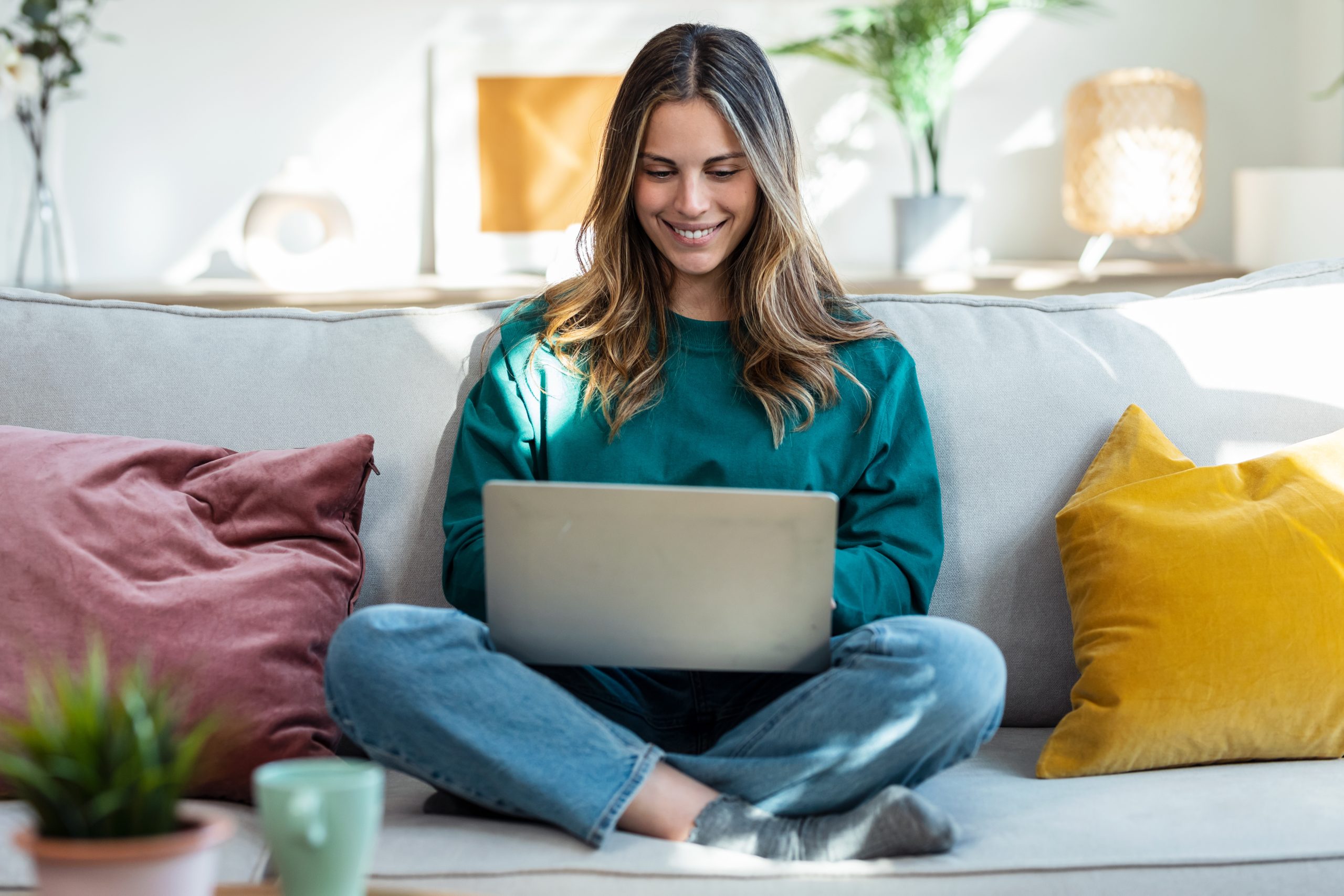 Shot of beautiful kind woman working with laptop while sitting on couch in living room at home